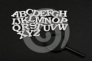 Latin letters in alphabetical order from A to Z. Black background. Magnifying glass