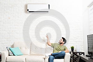 Latin Man Adjusting Temperature Of Mini Split At Home photo