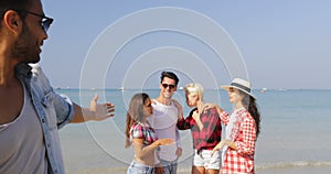 Latin Man Answer Phone Call With People Group On Beach Have Video Conversation On Cell Smart Phone