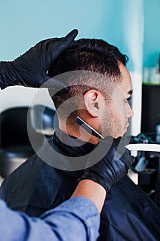 Latin man client getting haircut by hairdresser in Mexico city