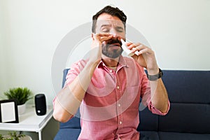 Latin man with a cold using a nasal spray photo