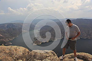 Latin man explorer in the viewpoint El Vigilante and in the background the Zimapan dam in Hidalgo Mexico