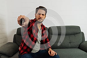 latin man with expression of concentration changing channel with remote control