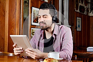 Latin man with headphones and digital tablet.