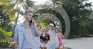 Latin Man Making Call Using Cell Smart Phone People Group Talking In Tropical Palm Tree Park