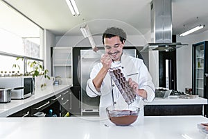 Latin man pastry chef wearing uniform in process of preparing delicious sweets chocolates at kitchen in Mexico Latin America