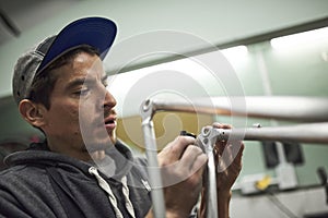 Latin man sanding a bicycle frame at his workshop