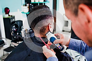 Latin man stylist cutting hair to a client in a barber shop in Mexico photo