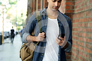 Latin man typing on his phone.