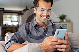 Latin man using smartphone at home photo