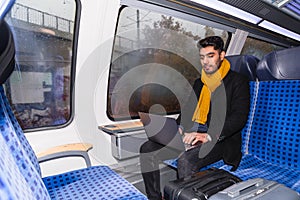 Latin man works on his laptop while riding train