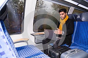 Latin man works on his laptop while riding train