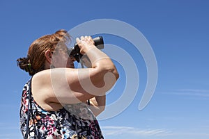 Latin mature woman looking through binoculars, Palmar National Park, Argentina