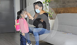 Latin mom and 3 year old girl with protective face masks and backpack for back to school, new normal covid-19