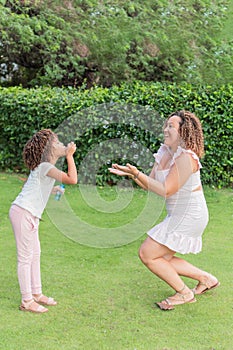 Latin Mother and daughter playing with bubbles in a park