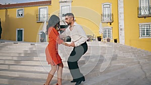 Latin performers practicing dance on town stairs. Happy couple dancing outdoors.