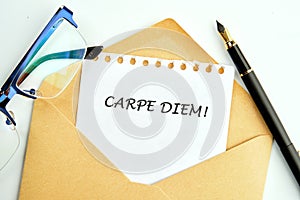 The Latin phrase Carpe Diem, a quote from Horace, means seize the moment. Live in the present written on a sheet in an envelope