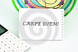 The Latin phrase Carpe Diem, a quote from Horace, means seize the moment. Live in the present written on a white card