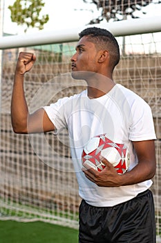 Latin soccer player with ball in hand celebrating a goal.