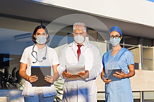 Latin team of medical doctors are looking at camera and smiling while standing outside of mexican hospital in Mexico city or latin