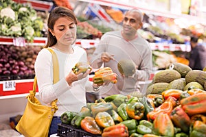 Latin woman choosing sweet pepper and man near choosing melon