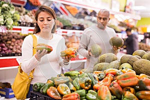 Latin woman choosing sweet pepper and man near choosing melon