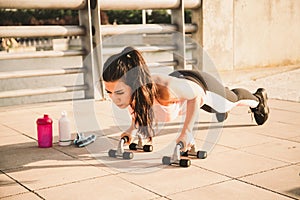 Latin woman does push-ups on the floor helped by two supports