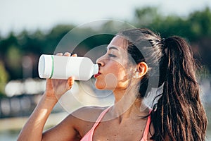 Latin woman drinks from a bottle of water after doing outdoor sports