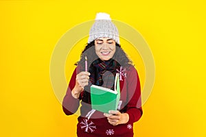 Latin woman holding christmas candles and singing carols on yellow background in Mexico Latin America