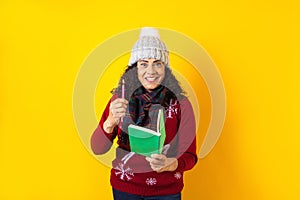 Latin woman holding christmas candles and singing carols on yellow background in Mexico Latin America