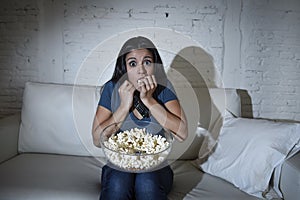 Latin woman at home sofa couch in living room watching tv covering eyes horrified photo