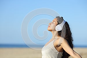 Latin woman listening to music and breathing on the beach