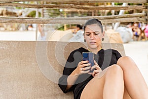 latin woman lying on a bed at the beach chatting on cell phone