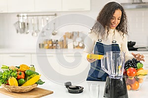Latin woman making juice in kitchen