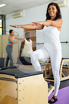 Latin woman perform exercises on combined chair