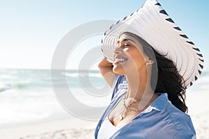 Latin woman relaxing on beach with white straw hat