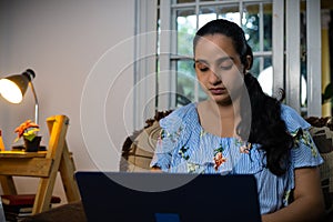 Latin woman typing on computer from her living room