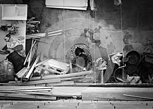 Latin woman washing clothes by hand in a messy backyard. Black and white, top down view