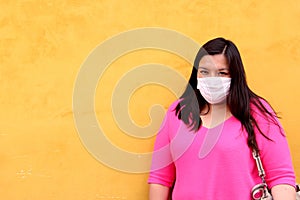 latin woman with white protection mask clinical use with colored background and walking in the street, new normal covod-19