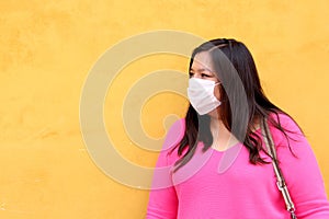 Latin woman with white protection mask clinical use with colored background and walking in the street, new normal covod-19