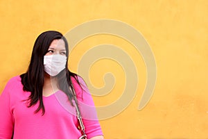 Latin woman with white protection mask clinical use with colored background and walking in the street, new normal covod-19