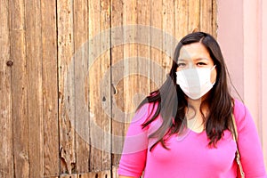 Latin woman with white protection mask clinical use with colored background and walking in the street, new normal covod-19