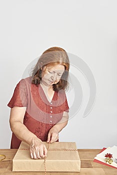 Latin woman wrapping Christmas gifts with neutral papers and decorative cords