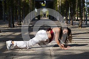 Latin woman, young and beautiful dancing modern dance in the street in a park and makes different expressions and postures.