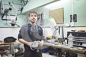 Latin worker standing in his workshop holding a protective respirator mask