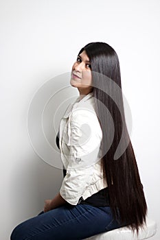 Latin young adult woman shows how silky and shiny her black hair is, very long, straight, very happy and proud of the beautiful ha