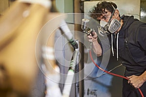 Latin young man concentrated spray painting a bicycle frame in his workshop