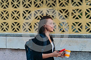 Latina businesswoman going to work in the morning. Woman walked to work holding a cell phone and hot coffee
