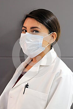 Latina female doctor wearing a clinical gown and masks for protection from covid-19