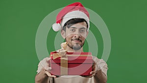 Latina Hispanic ethnic male wearing Santa Christmas festive hat man guy standing in studio green background giving